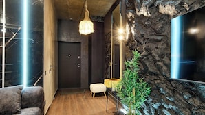 Un intérieur moderne avec un plancher en bois, un canapé gris, un luminaire suspendu, une petite table ronde et une plante en pot.