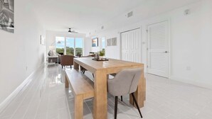 Un comedor moderno con una mesa de madera, bancos y sillas. Se observan ventanas con vistas a zonas verdes.