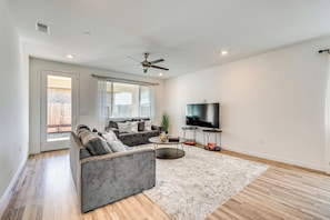 A modern living room with a grey sectional sofa, a coffee table, a flat-screen TV, and a ceiling fan. - 15 Mi to Dtwn Sacramento: Newly Built Home! (Sacramento)