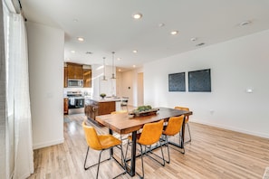 A modern kitchen with wooden cabinets, a microwave, and a dining area with a wooden table and orange chairs. - 15 Mi to Dtwn Sacramento: Newly Built Home! (Sacramento)