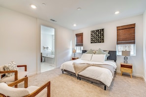 A bedroom with a large bed, bedside tables, a chair, and a view of the bathroom. - 15 Mi to Dtwn Sacramento: Newly Built Home! (Sacramento)