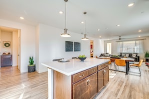 A modern kitchen with a central island, pendant lighting, and a dining area with a sofa and chairs. - 15 Mi to Dtwn Sacramento: Newly Built Home! (Sacramento)