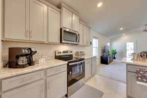 A modern kitchen with white cabinetry, stainless steel appliances, and a large island.
