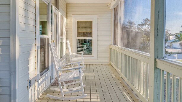 A porch with white railings and a rocking chair.