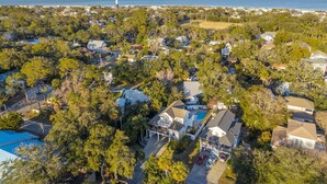 An aerial view of a residential area with houses, trees, and a lighthouse in the distance.