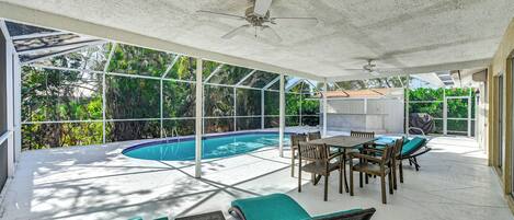 A covered outdoor area with a pool, seating, and a ceiling fan.