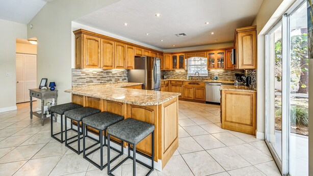 A spacious kitchen with wooden cabinets, a granite countertop, and a large island with bar stools.