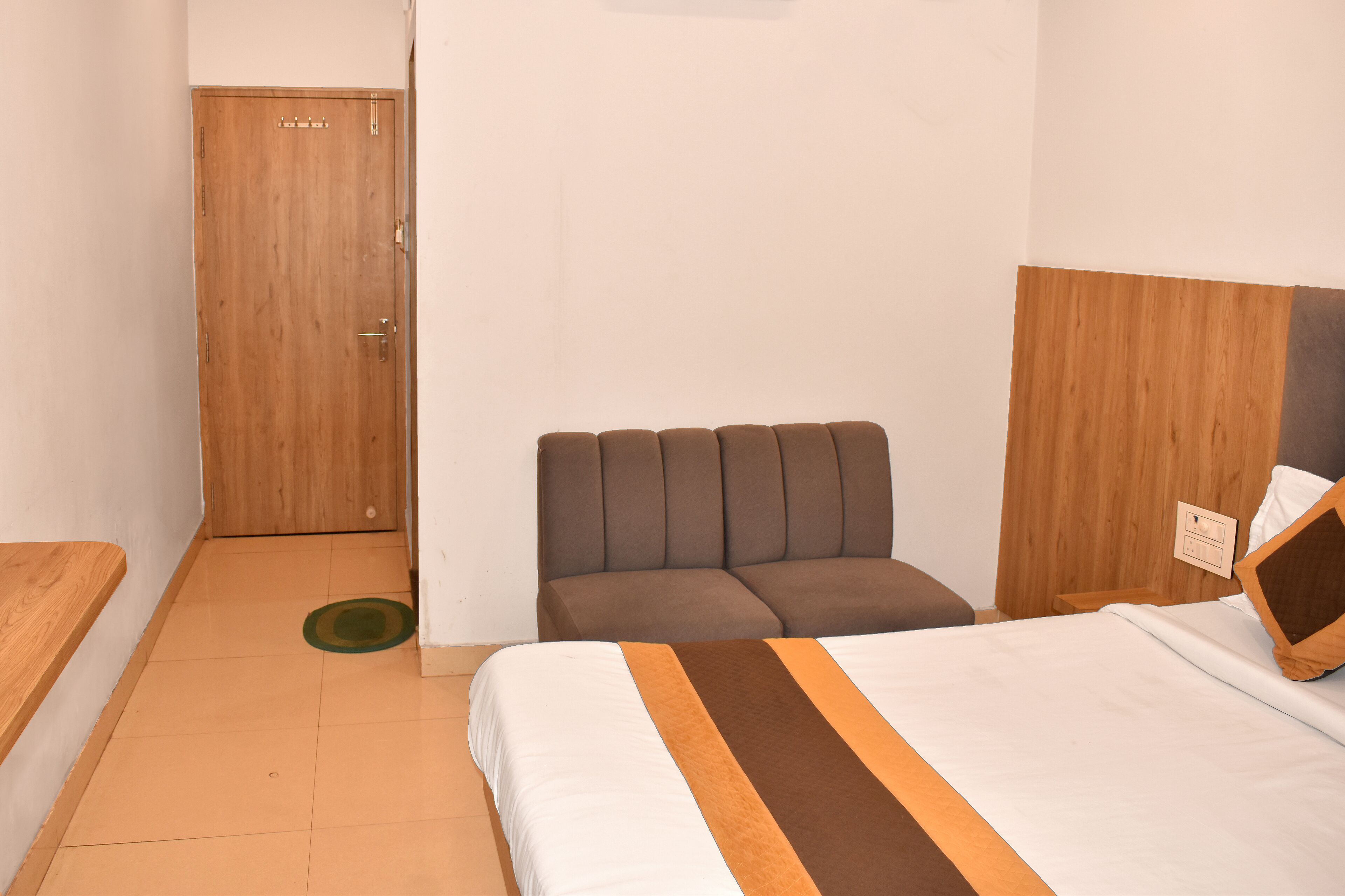 A hotel room with a bed, a sofa, a wooden door, and a small table.