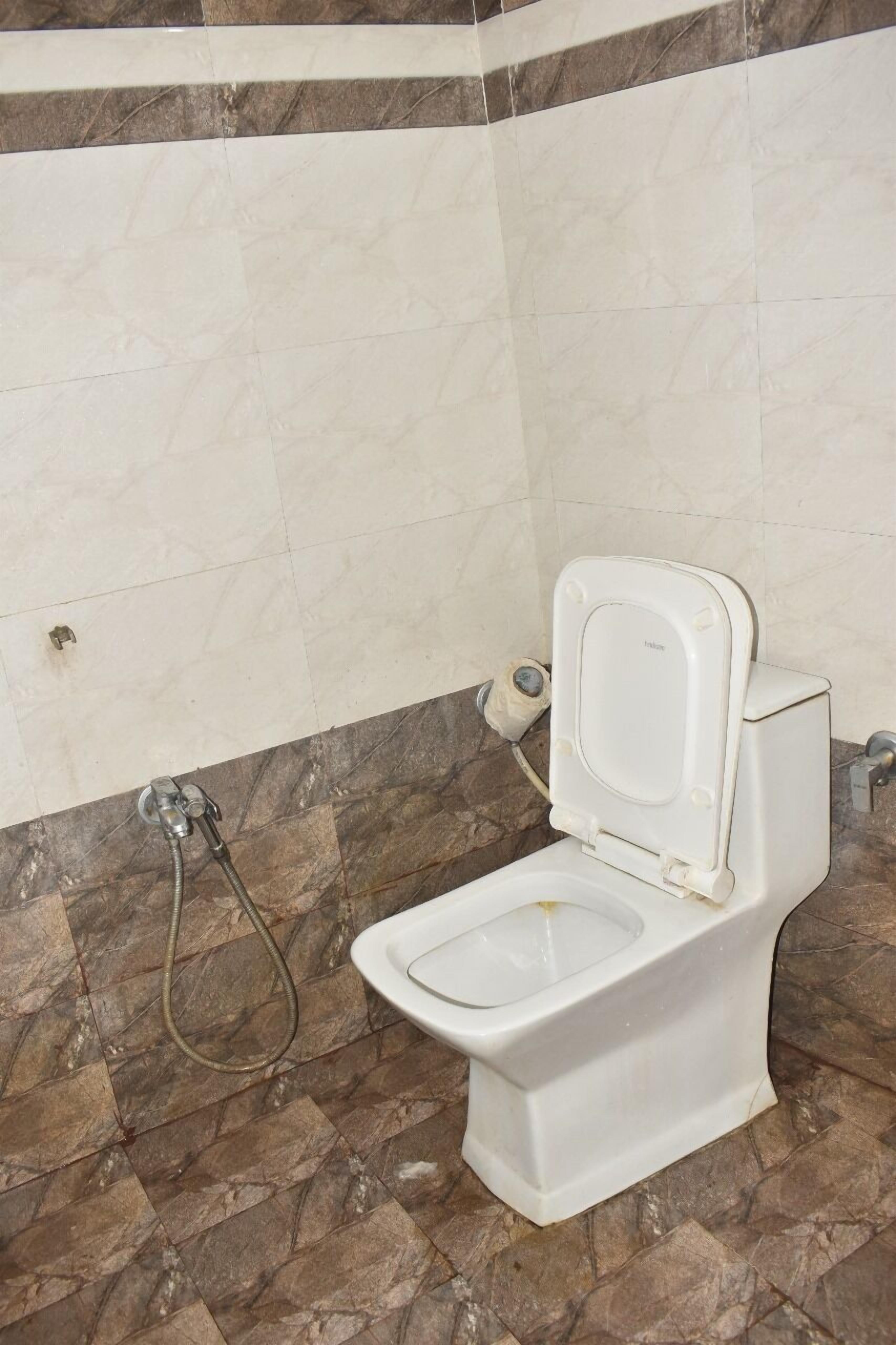 Een badkamer met een wit toilet, marmeren tegels en een douchehoek.
