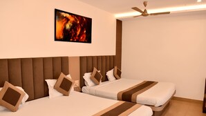 Une chambre d’hôtel avec deux lits, un ventilateur de plafond et un tableau au mur.