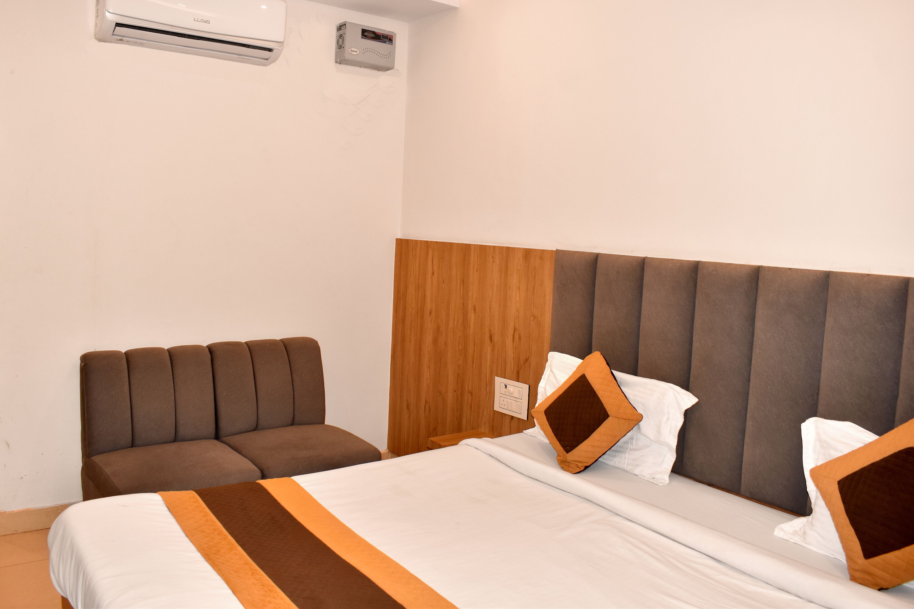 A hotel room with a bed, a sofa, and a wooden headboard.