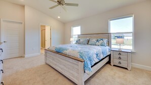 Ein Schlafzimmer mit Bett, Nachttisch, Fenster und Deckenventilator.