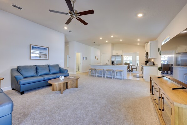 A spacious living room with a blue sofa, a wooden coffee table, and a ceiling fan.