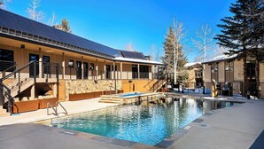 Ein modernes Gebäude mit Pool, Holzfassade und einer Treppe zu einer Terrasse.