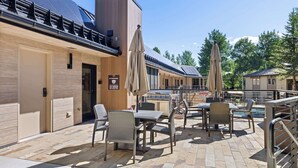 Ein Terrassenbereich im Freien mit Korbmöbeln, Grill und Pool.