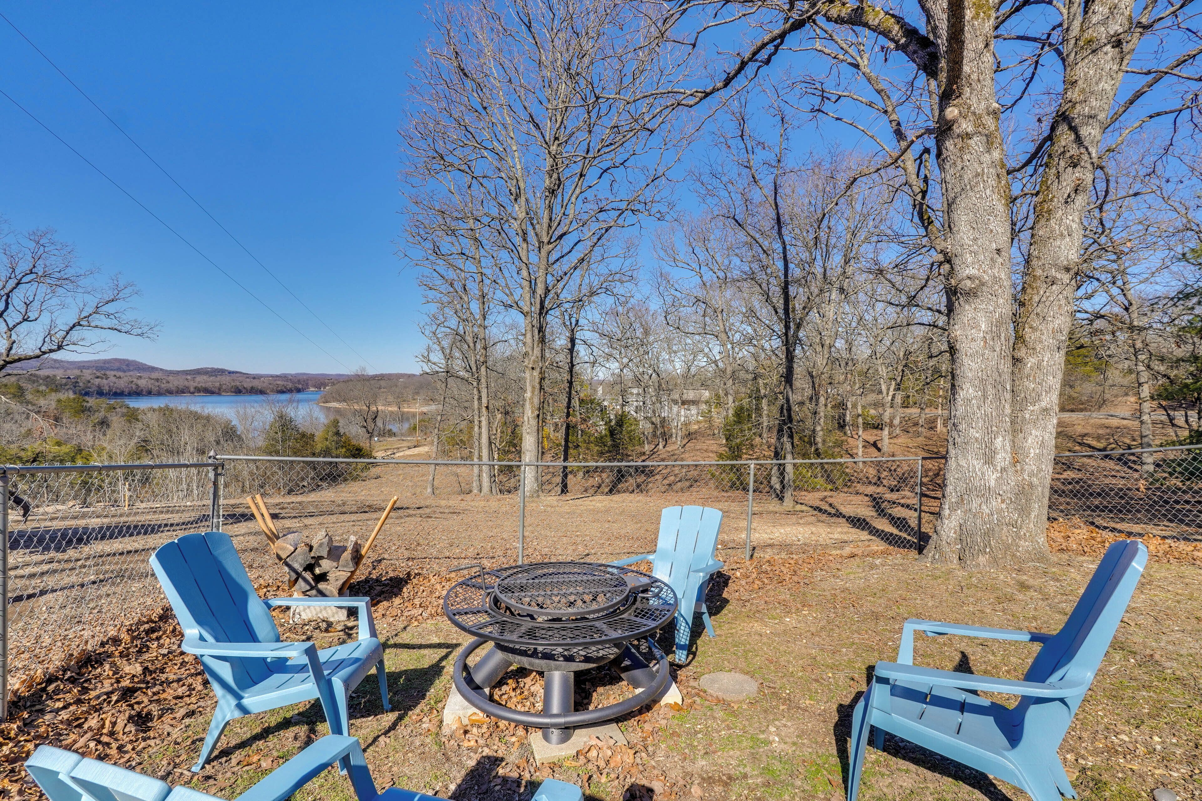 A patio with two blue Adirondack chairs and a circular fire pit.