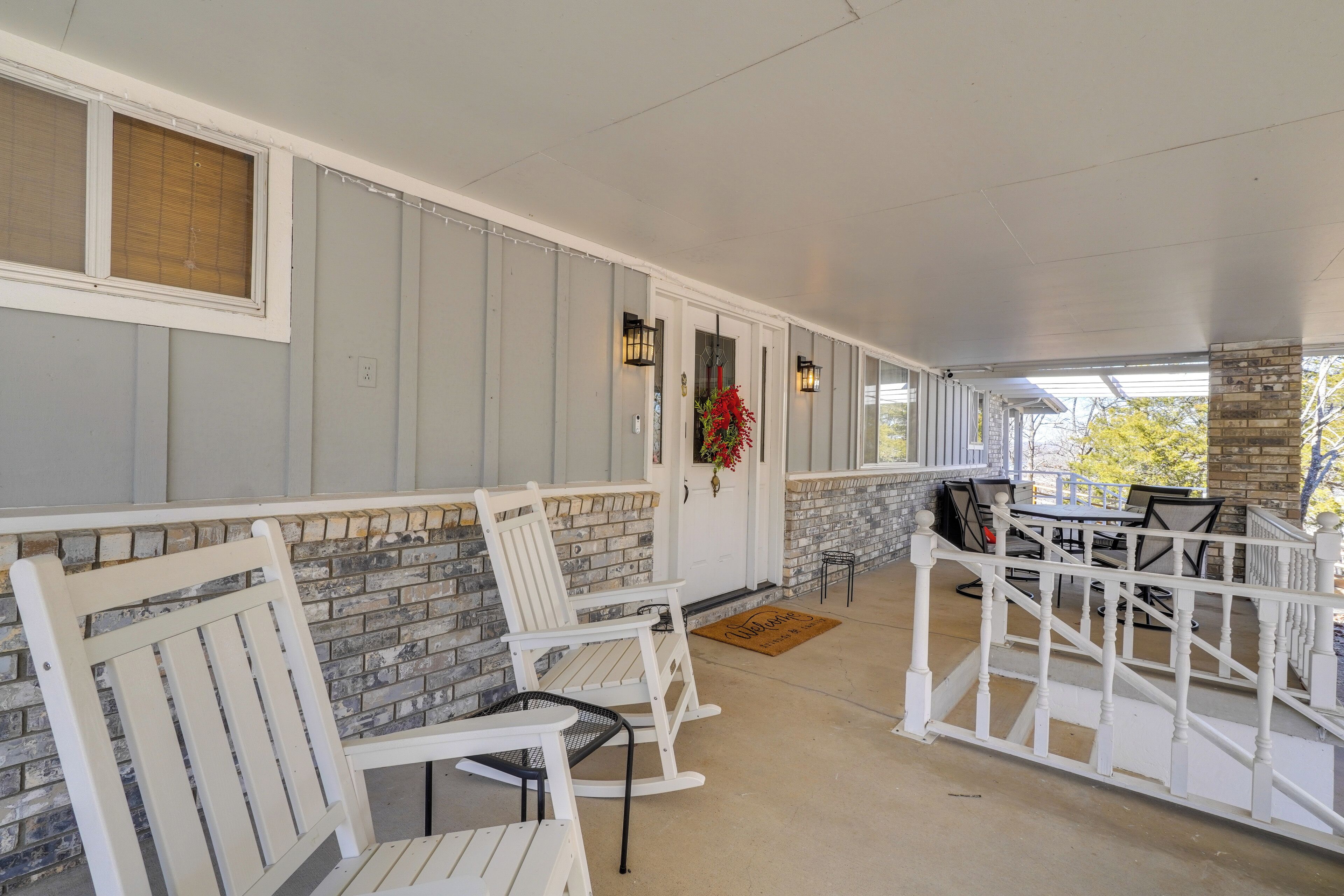 A covered porch with white rocking chairs and a brick wall.