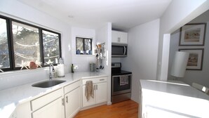 Una cocina moderna con armarios blancos, un lavamanos de acero inoxidable, un microondas y un horno.