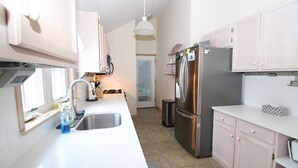 Una cucina moderna con piani di lavoro bianchi, elettrodomestici in acciaio inossidabile e mobili chiari.
