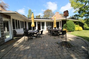 Une terrasse extérieure avec une table et des chaises, entourée d’un espace abrité agrémenté de parasols jaunes.