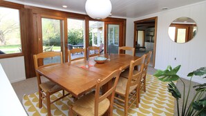 Un coin repas avec une table et des chaises en bois, un saladier et une suspension.