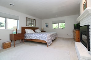 A bedroom with a bed, nightstand, dresser, and a fireplace.