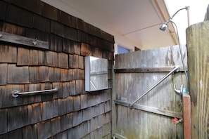 A wooden exterior wall with metal fixtures, including a handrail and a metal box. - Spacious Home With Private Yard Close to Beach Abutting Conservation (2397) (Brewster)
