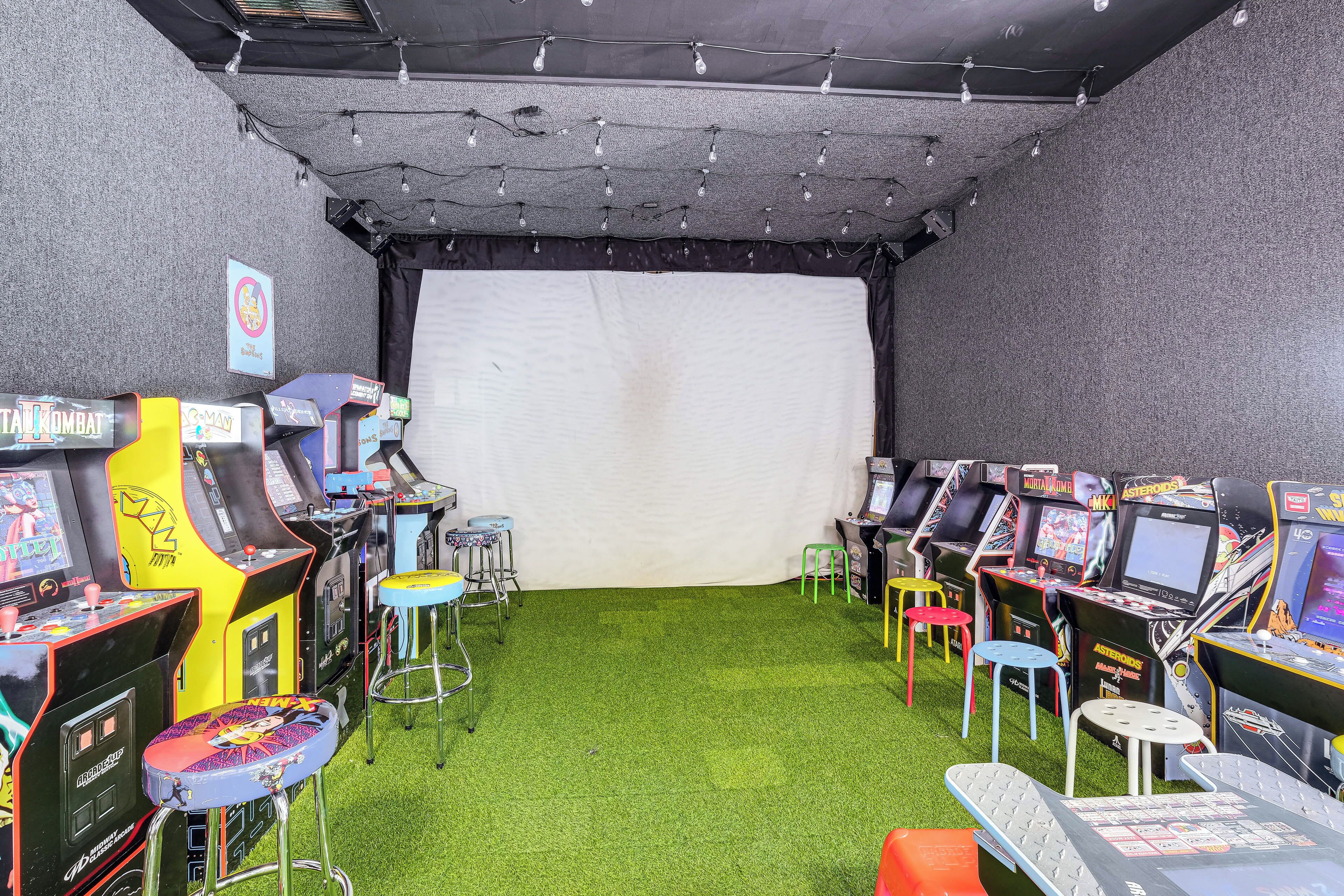 Ein Spielbereich mit mehreren Spielautomaten, synthetischem Rasen und Hockstühlen.