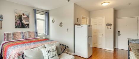 Un dormitorio con cama, sofá, refrigerador y puerta que da a un baño.