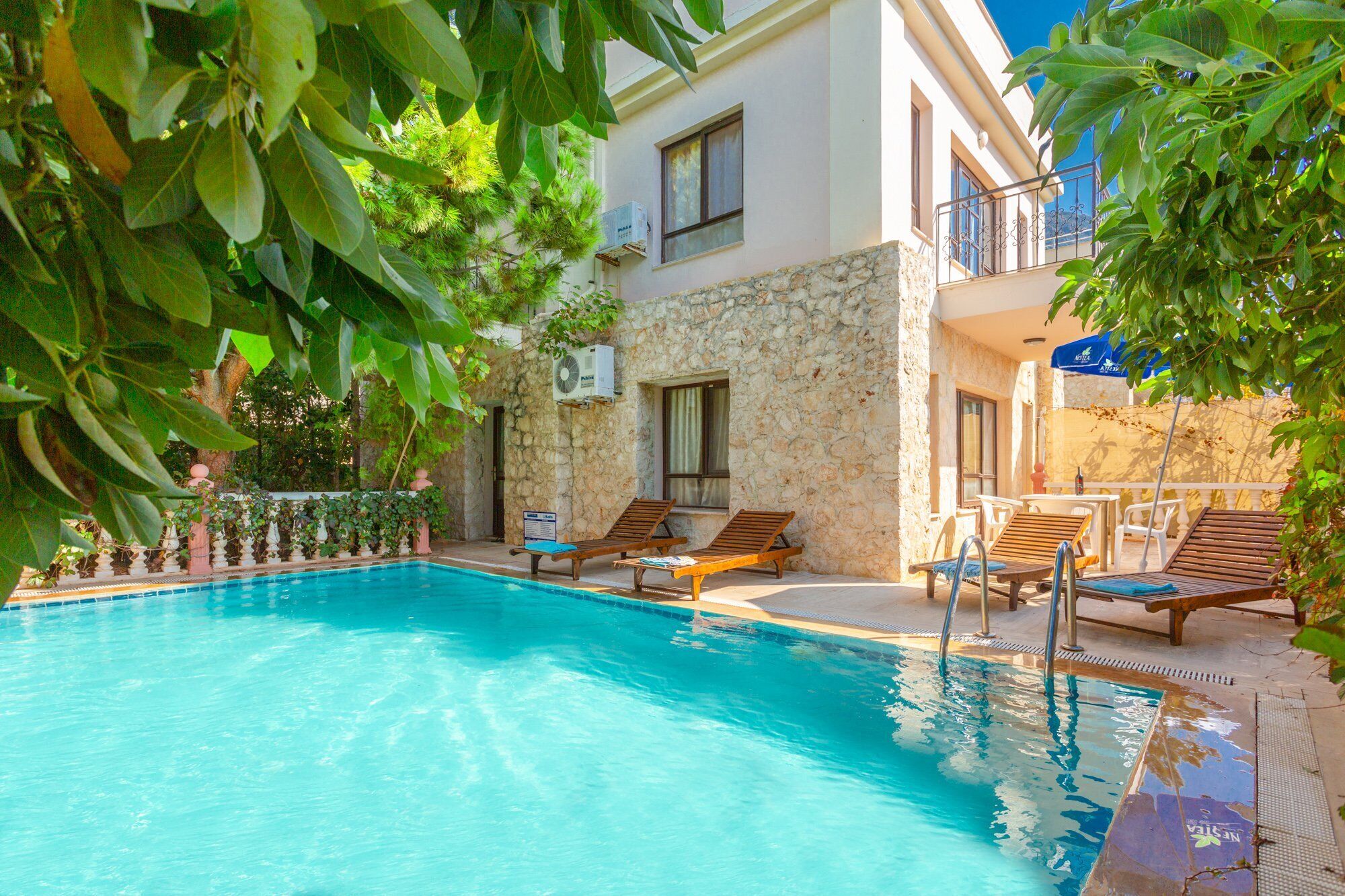 Un área de piscina con sillones de descanso y una pared de piedra.