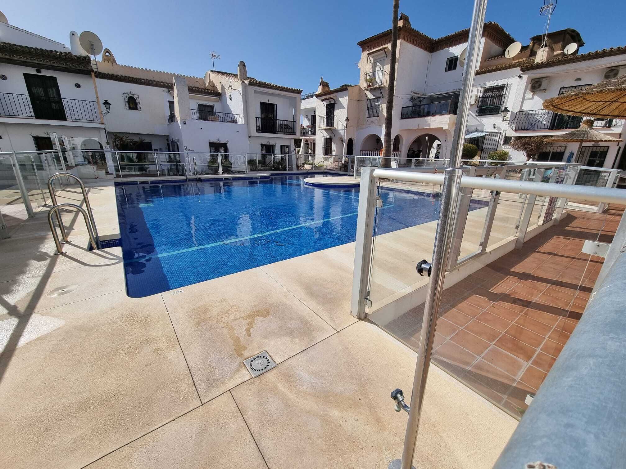 Piscina com barreira de vidro, rodeada por edifícios com varandas e antenas parabólicas.