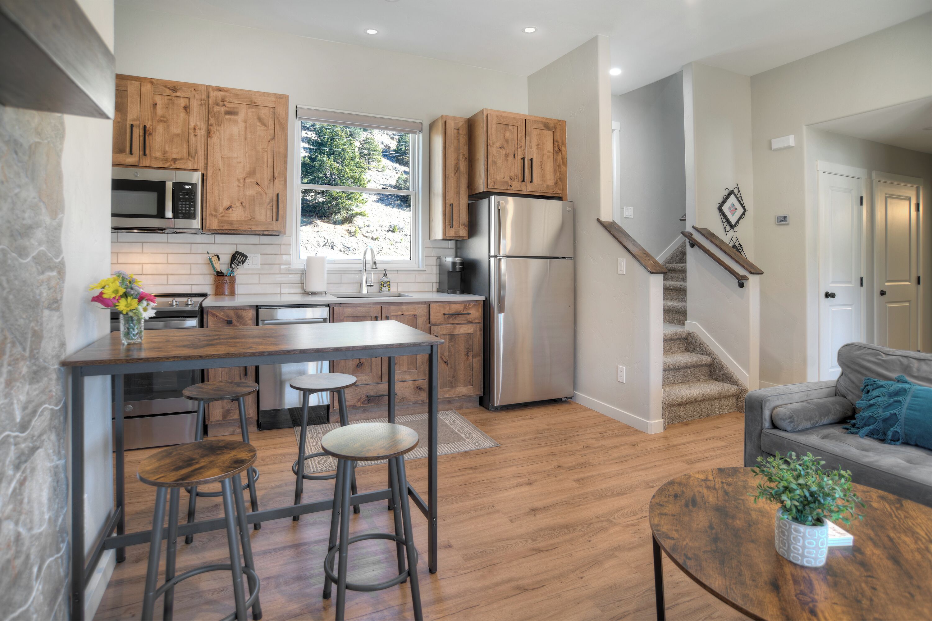 Une cuisine moderne avec des meubles en bois, des appareils en acier inoxydable et un îlot central doté de tabourets.
