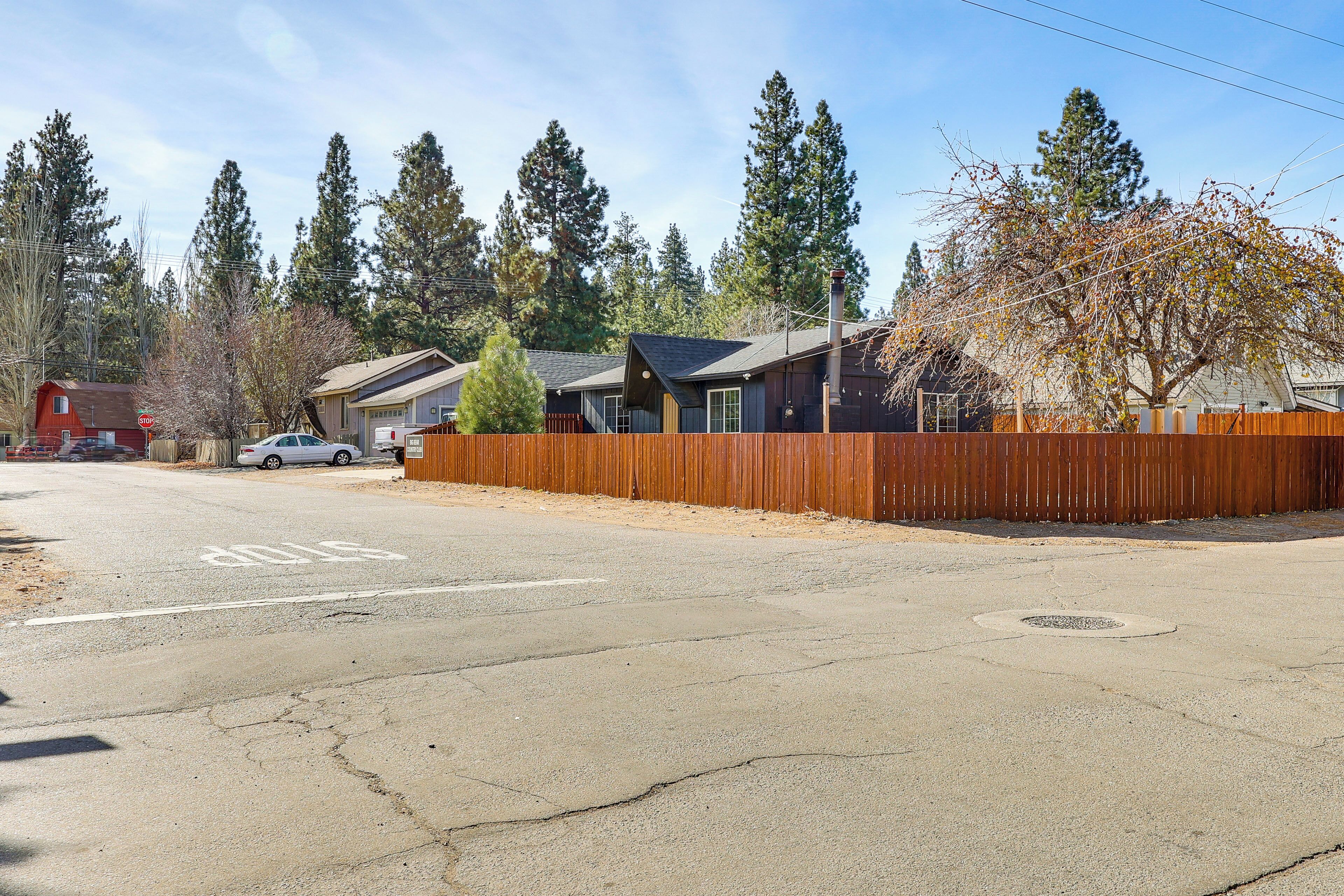 A residential street with houses, a stop sign, and a wooden fence.
