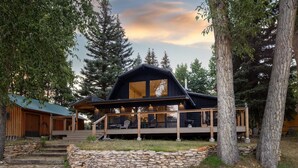 A cabin with a stone foundation, wooden deck, and large windows.