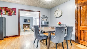 A dining area with a wooden table and grey upholstered chairs, a wall clock, and a decorative ceiling. - 4 Mi to Dtwn Kalamazoo: Central Apt (Kalamazoo)