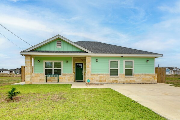 A single-story house with a green door, a front porch, and a small front yard. - Modern Port Isabel Home: Coastal Family Home! (Port Isabel)