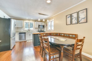 A kitchen with a dining area, wooden cabinets, a black refrigerator, and a large island.