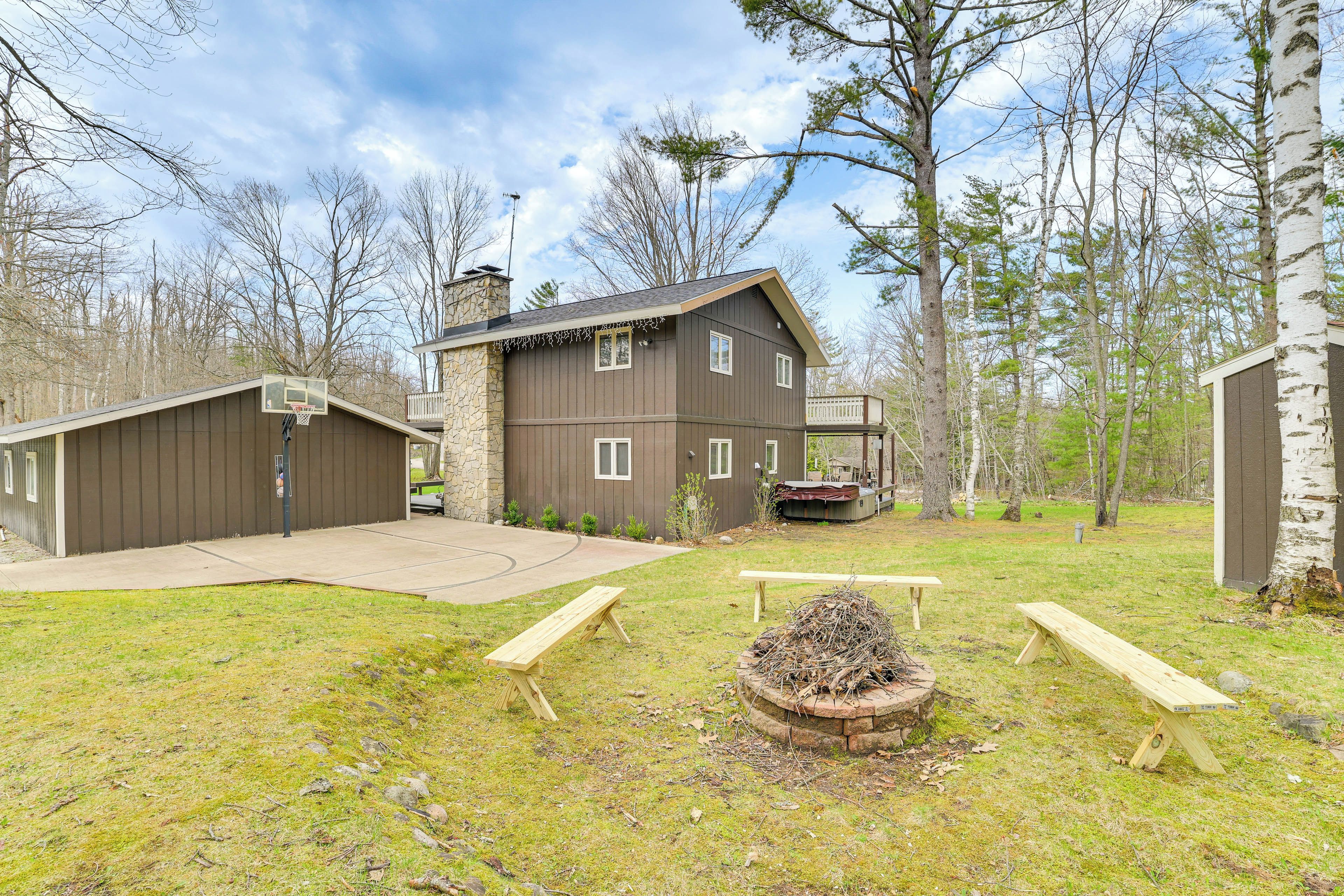A two-story house with a stone chimney, a basketball hoop, and a fire pit.