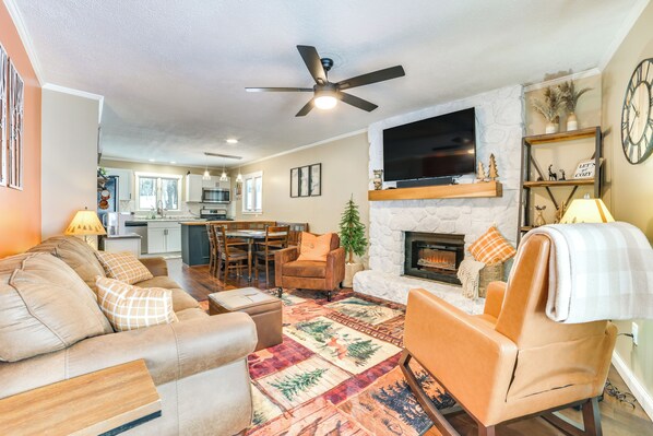 A living room with a fireplace, a ceiling fan, and a television mounted above it. - Private Hot Tub & Deck: Gaylord Family Home! (Gaylord)