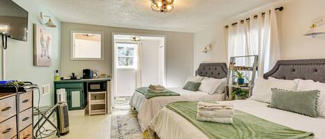 A bedroom with two beds, a desk, a chair, and a television.