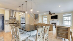 Una cocina amplia con una isla central, sillas de madera e iluminación colgante.
