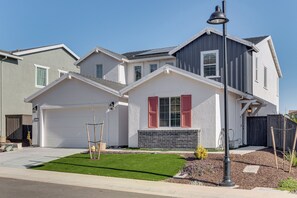 A modern two-story house with a white garage door, a small front yard with a lawn and a wooden deck, and a street lamp. - 7 Mi to Folsom Lake: Sacramento Area Apartment (Folsom)