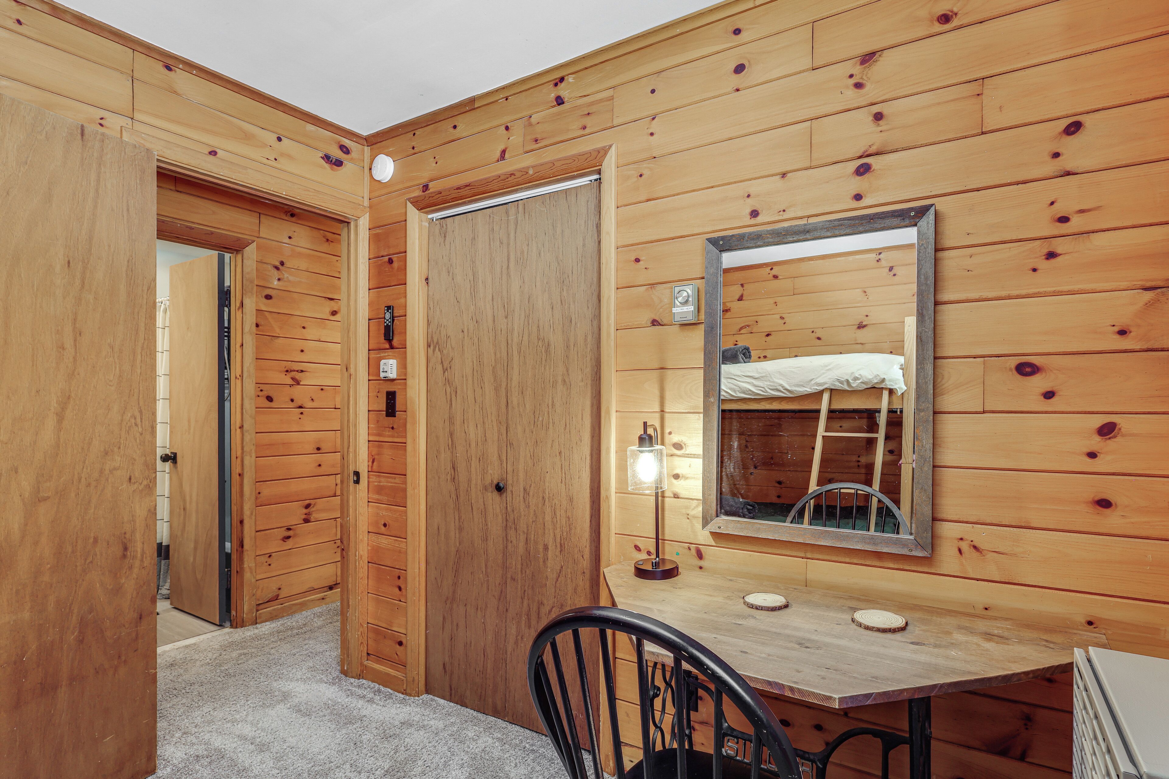 A wooden-paneled room with a bed, a desk, and a chair.