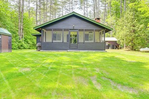 A two-story cabin with a green roof, large windows, and a front door.