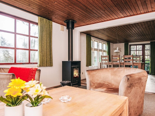 Un salon chaleureux avec une cheminée, des meubles en bois et de grandes fenêtres.