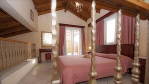 A bedroom with a large bed, a desk, and a window with curtains.