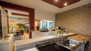 Una cocina moderna con una isla central, horno empotrado y pileta de acero inoxidable.