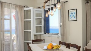 Un espace repas comprenant une longue table, des chaises, un luminaire suspendu et une vue par la fenêtre.