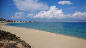 Une plage à l’eau turquoise et limpide, avec un rivage sablonneux, où quelques personnes se détendent.