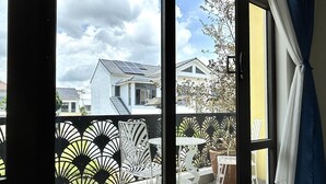A balcony with a view of neighboring houses, a metal fence, and a table with chairs.
